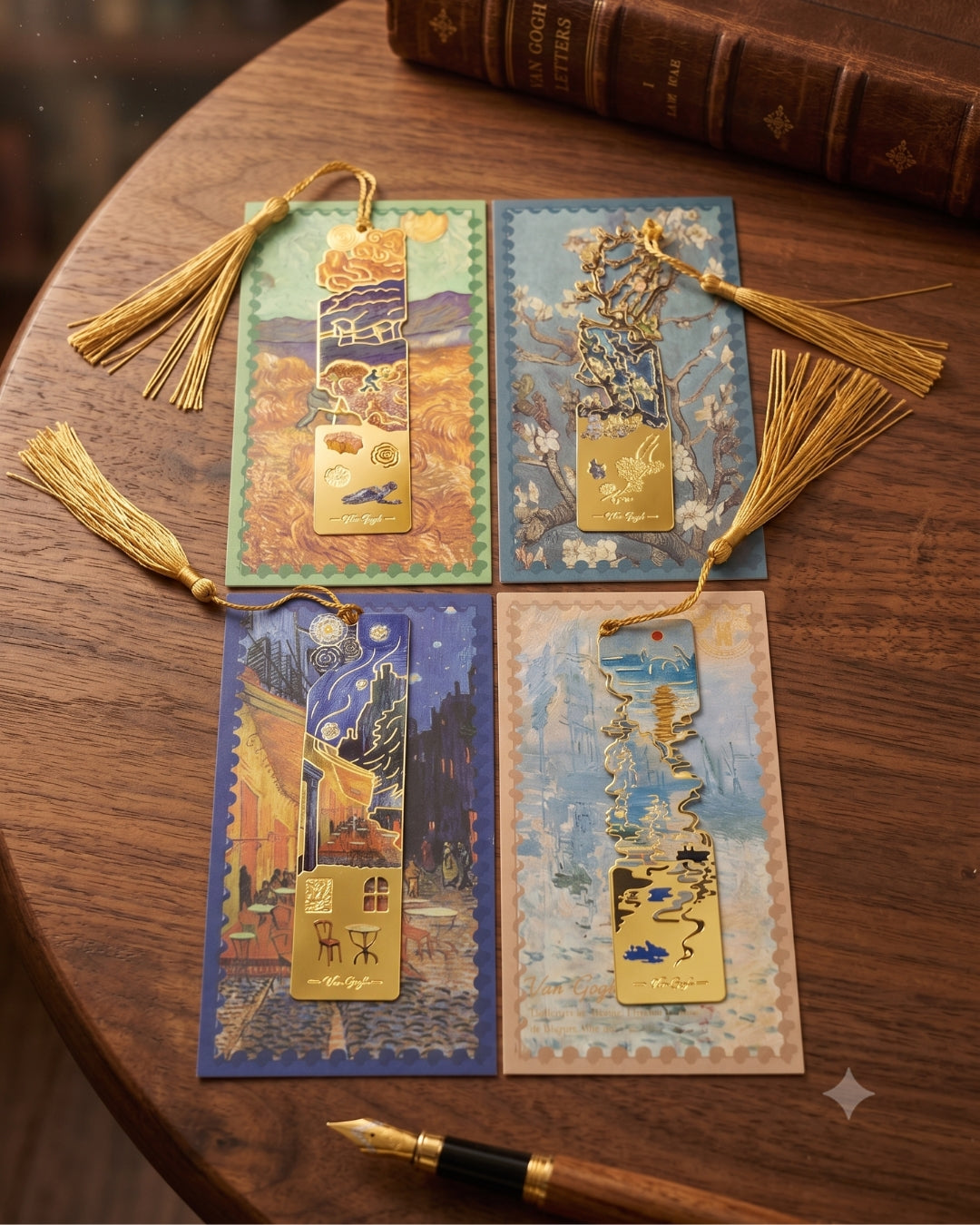 Four Van Gogh-inspired bookmarks with gold tassels are laid out on a wooden table next to a vintage book and a fountain pen.