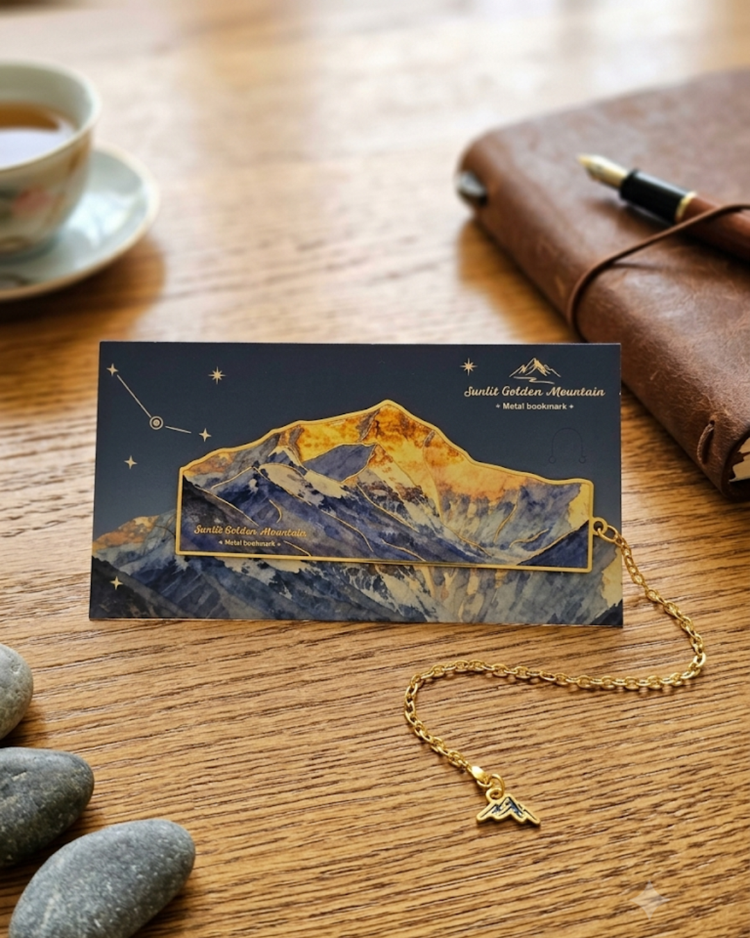 A bookmark featuring a golden mountain range under a dark blue starry sky, with a gold chain and mountain charm attached.