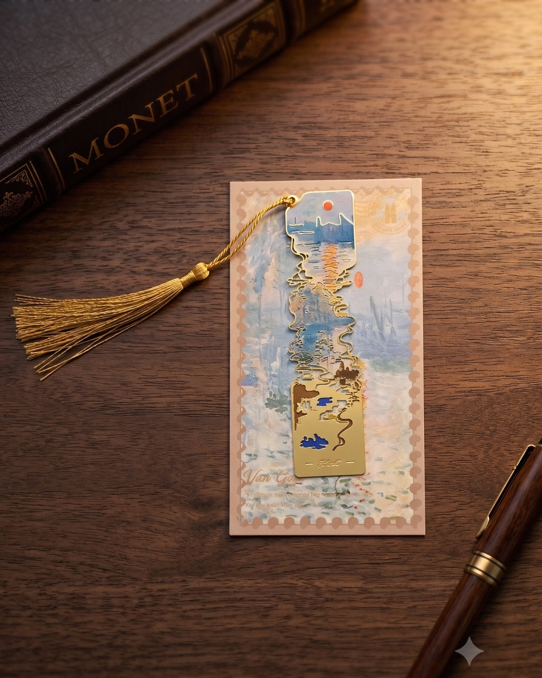A bookmark shaped like a Monet painting, with a gold tassel, rests on a wooden surface next to a book titled "Monet" and a fountain pen.