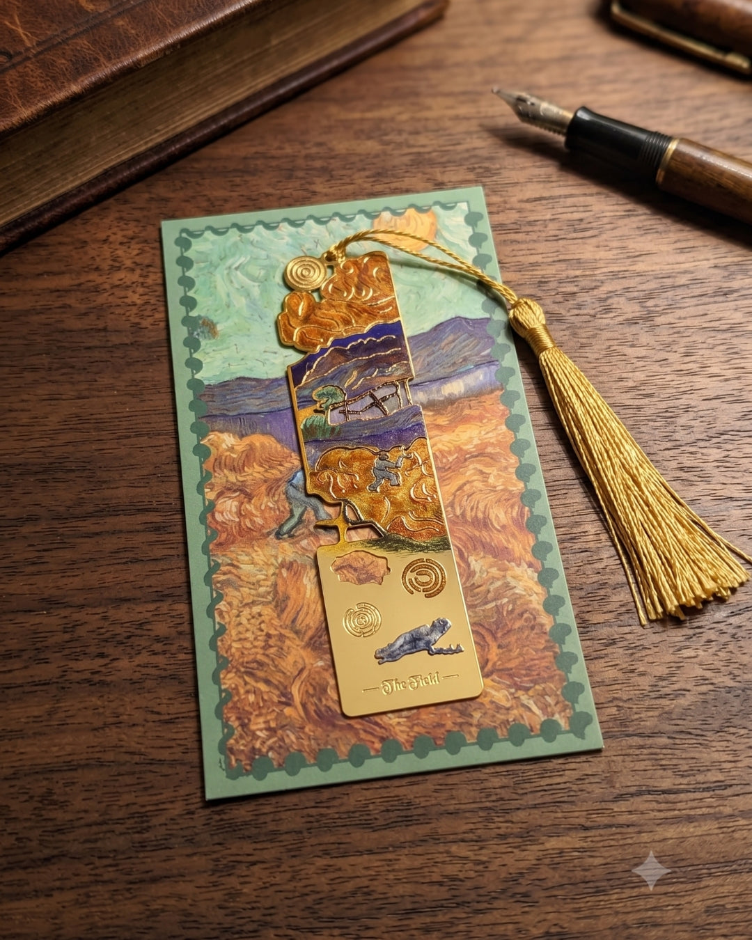 A gold bookmark with a tassel, inspired by Van Gogh's "The Starry Night", rests on a postcard featuring a depiction of the same painting. A vintage book and fountain pen are visible in the background.