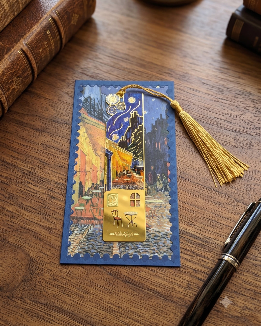 A bookmark featuring Van Gogh's "Cafe Terrace at Night" painting, adorned with a gold tassel and decorative charms.