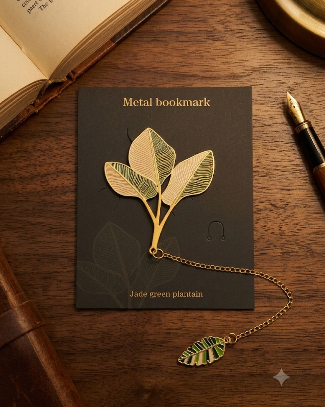 A metal bookmark shaped like a plantain leaf stem with three leaves and a decorative smaller leaf attached by a gold chain. The bookmark is displayed on a dark card with the text "Metal bookmark" and "Jade green plantain".