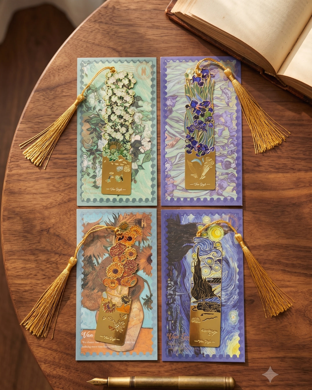 Four bookmarks with gold tassels are laid out on a wooden table next to an open book. The bookmarks depict floral designs and Van Gogh's Starry Night.